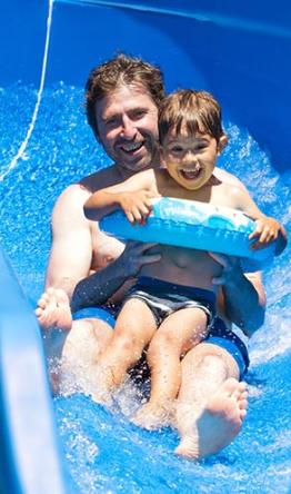 Padre e figlio sorridenti su uno scivolo d'acqua.